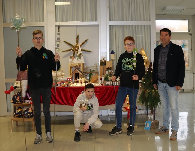 Maximilian, Jerome und Liam präsentieren gemeinsam mit Schulleiter Christian Haag einen ersten Eindruck von den schönen und leckeren Produkten, welche die Besucherinnen und Besucher auf dem „Sternenzauber“-Basar am 23. November erwarten.
