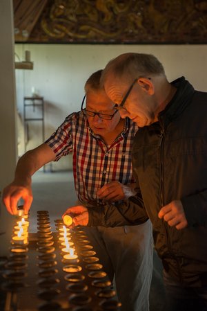 Zwei Männer zünden Kerzen in der Kirche an.